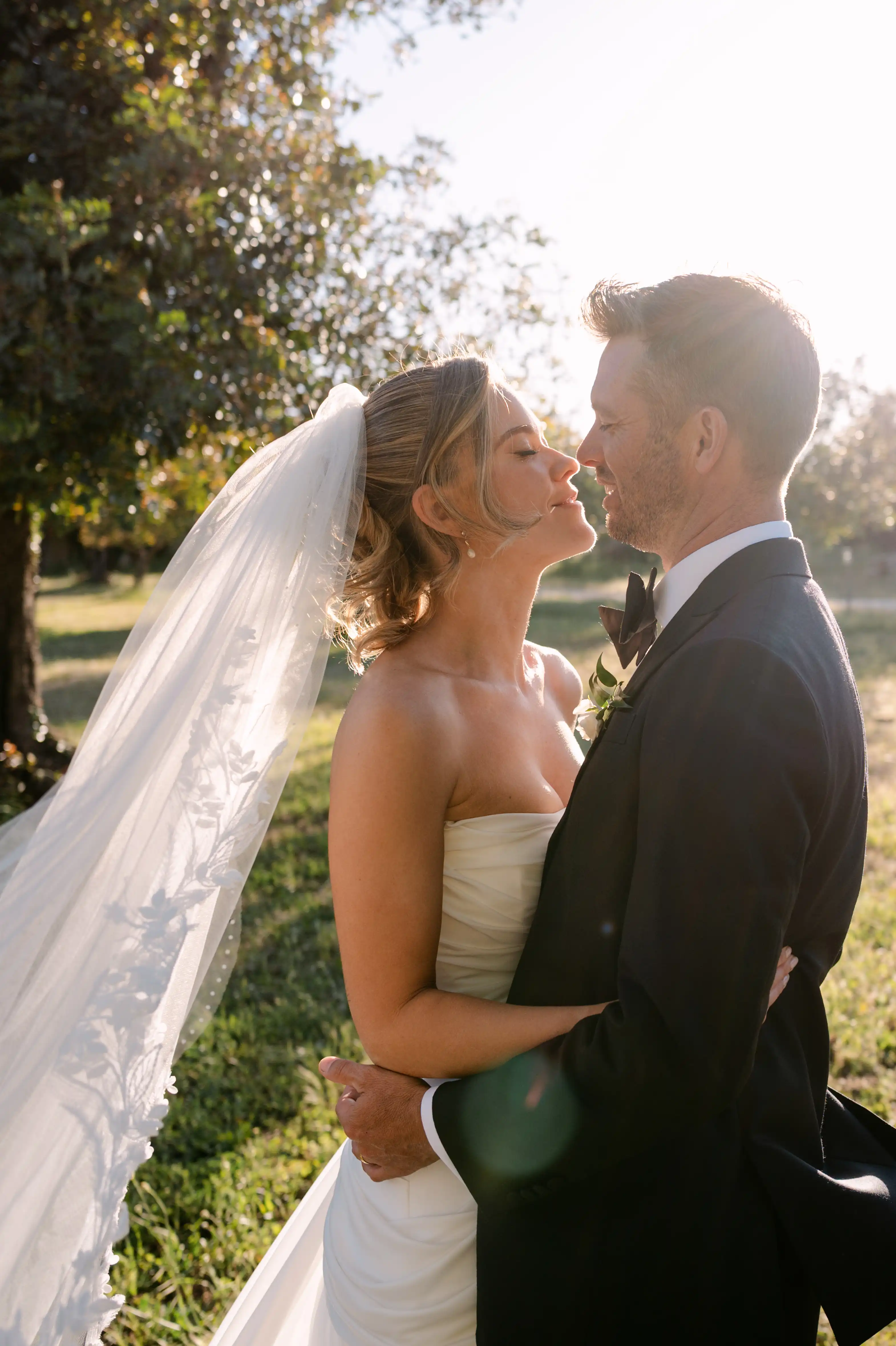 Romantic sunset portrait of bride and groom embracing outdoors in the Sicilian countryside.